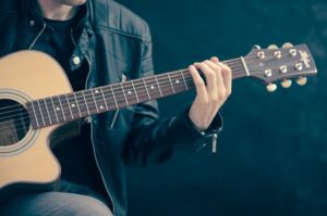 close up of man playing guitar.